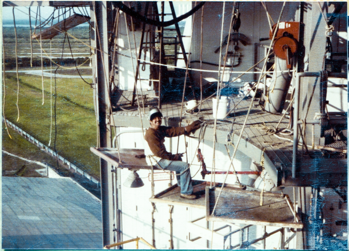 Image 057. Union Ironworker Dave Skinner, working for Ivey's Steel Erectors at Space Shuttle Launch Complex 39-B, Kennedy Space Center, Florida, takes a momentary lighthearted break from his work in the area of the Orbiter Mold Line, at RSS Elevation 125’-0”, calmly sitting on a float, above a free drop of seven stories to the concrete surface of the Pad Deck, directly below him. Photo by James MacLaren.